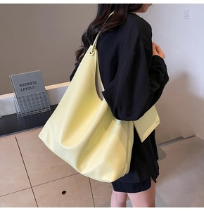 Gros plan d'un sac cabas en cuir grainé jaune avec petit porte-monnaie assorti attaché