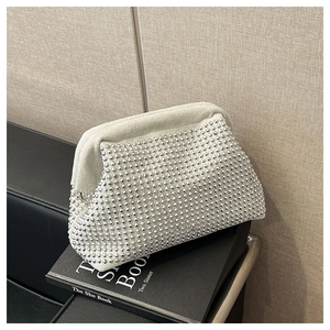 Detailed close-up of a silver rhinestone-studded clutch bag resting on a black book
