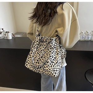 Detail view of large leopard print canvas tote bag with black strap on a shoulder