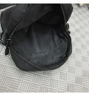 Top down view of the main compartment and zipper closure of the black nylon crossbody bag