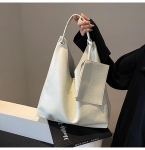 Détail du cabas blanc cassé montrant la texture du cuir grainé et une petite pochette