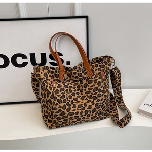 Detailed close-up of leopard print canvas tote bag with brown faux leather handles and straps