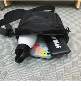 Macro detail of spacious black crossbody bag showing its interior capacity with daily items