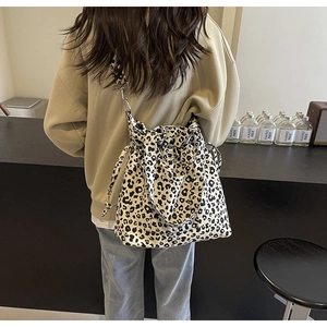 Detail of leopard print canvas tote bag with drawstring closure on model's shoulder