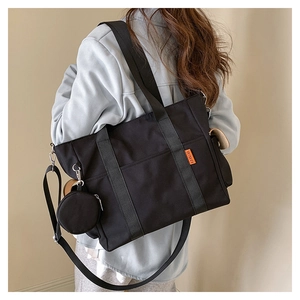 Black canvas tote bag featuring an adjustable strap and a small round coin purse attachment