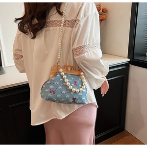 Close-up of denim shell bag with butterfly embroidery and pearl strap details