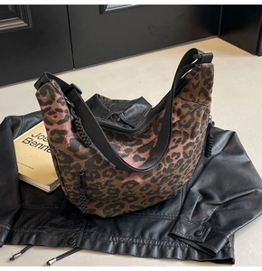 Detail of hobo bag with leopard print canvas and black shoulder strap on black leather