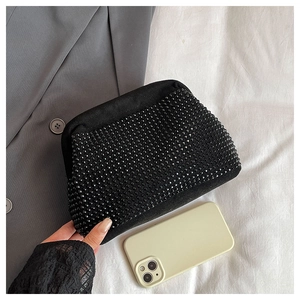 Detail of black rhinestone evening bag held by hand showing compact size and texture