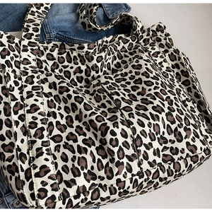 Dettaglio ravvicinato della borsa tote in tela leopardata con tasche frontali funzionali