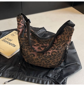 Close-up of leopard print crescent crossbody bag with woven zipper details and wide strap