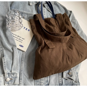 Detail of coffee brown canvas tote bag featuring contrast stitching and sturdy straps