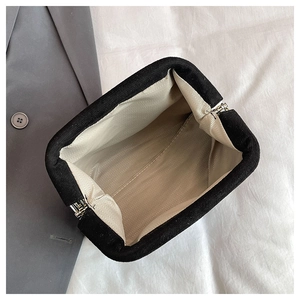 Detailed interior of black shell bag with beige herringbone lining and silver metal frame