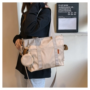 Detail of a large beige nylon tote bag with side coin purse and crossbody strap