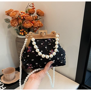 Detail of sequin butterfly handbag with wooden clasp and glossy pearl handle