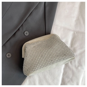 Detailed close-up of French shell evening bag with sparkling rhinestones on grey blazer