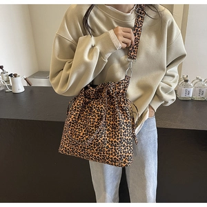 Detail of leopard print canvas bucket bag showing drawstring closure and wide shoulder strap