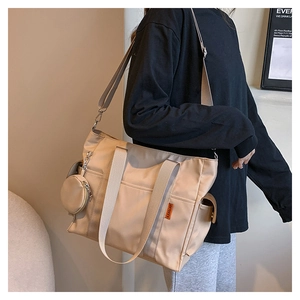 Detail of beige nylon tote bag with adjustable strap and side coin purse attachment