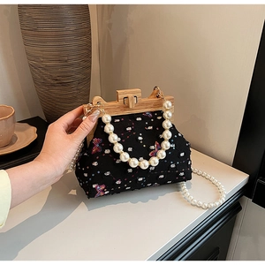 Detail of black shell bag with colorful sequins, butterfly embroidery and wooden clasp