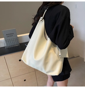 Détail de la texture cuir grainé d'un grand sac cabas blanc crème avec petite pochette