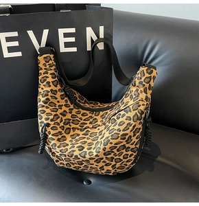 Detail showing high-quality leopard print canvas texture and black nylon strap on hobo bag