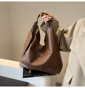 Détails de la texture du cuir litchi marron et de la poignée nouée sur le sac cabas