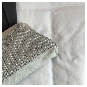 Close-up of sparkling silver rhinestones on a luxury evening shell bag fabric