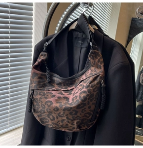 Close-up of leopard print canvas dumpling bag with adjustable strap and braided zipper