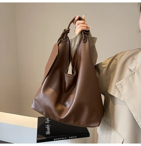 Détail du cabas en cuir grainé marron foncé avec poignée nouée et accessoire latéral