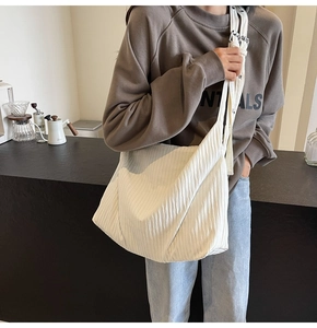 Detail der weißen Plissee-Cordtasche mit weicher Textur und verstellbarem Riemen