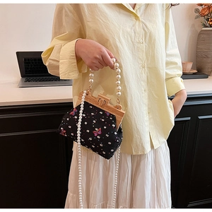 Detail of vintage black butterfly print bag with wooden frame and pearl bead handle