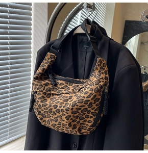 Detail of leopard print canvas crescent bag with adjustable strap and braided zipper pull