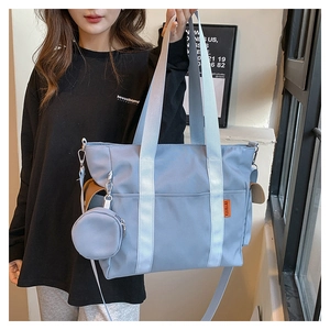 Detail of light blue nylon tote bag with adjustable shoulder strap and round mini pouch