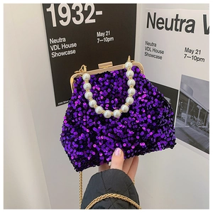Detail der lila Pailletten-Handtasche mit weißem Perlengriff und goldenem Schnappverschluss