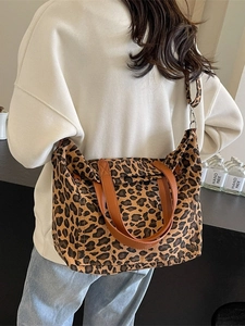 Leopard print canvas tote bag with brown leather handles and adjustable shoulder strap