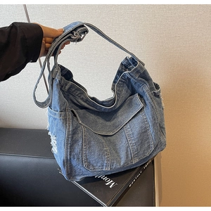Detail showing distressed denim texture with fringe and side pocket of the crossbody bag