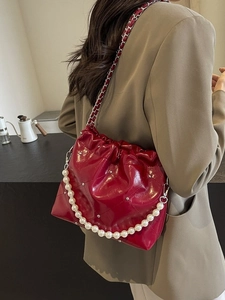 Quilted red bucket bag with pearl handle and chain strap worn by a model