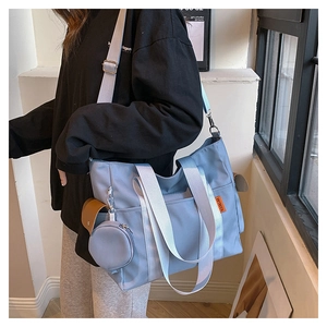 Detail of light blue nylon tote bag with wide strap and round coin purse attachment