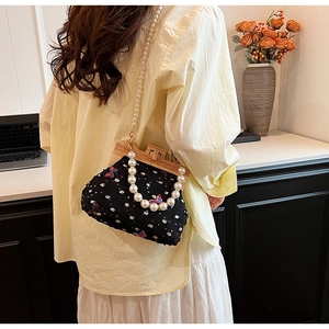 Detail of crossbody shell bag with butterfly embroidery and pearl strap on model