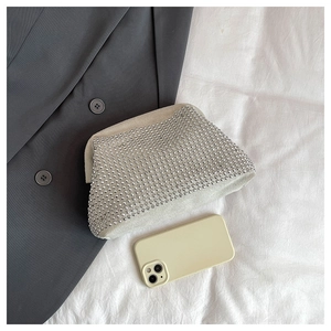 Detailed flat lay of a rhinestone evening clutch bag on a suit jacket and white cloth