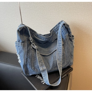 Close-up of denim tote bag with silver chain decor and distressed frayed edge details