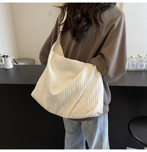 Nahaufnahme einer weißen Cord-Tasche mit feiner Rippstruktur an einem weiblichen Model