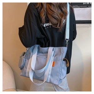 Detail of light blue nylon tote bag with round coin purse and adjustable strap