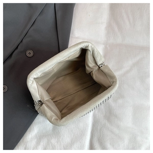 Macro detail of luxury shell bag interior showing beige fabric lining and rhinestones