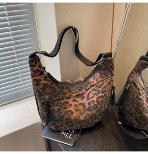 Detail of leopard print canvas crescent bag with black nylon strap and braided zipper pull