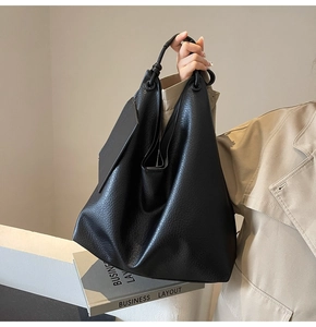 Détail du grand sac cabas noir avec texture grainée de litchi et pendentif carré élégant