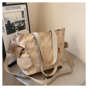 Detail of khaki nylon tote bag featuring side hooks and a small round coin purse charm