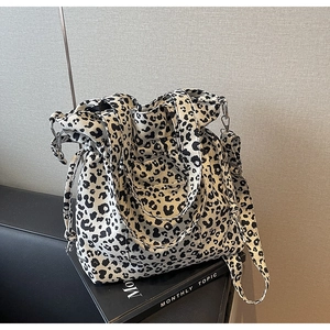 Detail of leopard print canvas tote bag with metal buckles and drawstring closure
