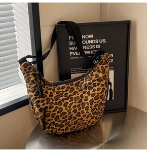 Detailed macro view of leopard print canvas crescent bag with black adjustable strap