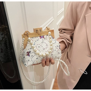 Detail of beaded shell bag with butterfly embroidery and elegant wood frame closure