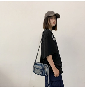 Detail view of the washed denim crossbody bag featuring multiple front zipper pockets